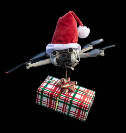 Photo for Drone concept wearing a santa hat and holding a wrapped gift out for delivery isolated on a black background. - Royalty Free Image