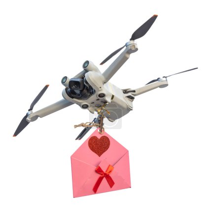 Téléchargez les photos : Drone isolé sur fond blanc délivrant une lettre d'amour dans une enveloppe rose avec un cœur et un ruban rouge. - en image libre de droit