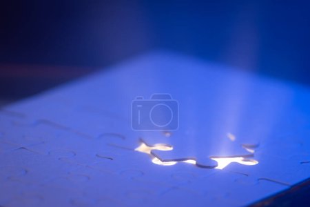 Téléchargez les photos : Gros plan d'un puzzle vierge avec une lumière bleue et un faisceau de lumière d'en dessous comme un concept. - en image libre de droit