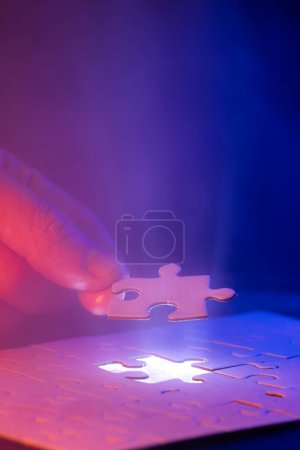 Téléchargez les photos : Gros plan d'une main tenant la pièce de puzzle manquante avec une lueur montrant où la pièce va et un peu de brouillard dans l'air. - en image libre de droit
