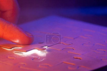 Photo for Close up of a hand holding the missing puzzle piece with a glow showing where the piece goes and a bit of mist in the air. - Royalty Free Image