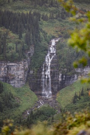 Foto de Hermoso y dramático paisaje en el Parque Nacional Glaciar con altas montañas dentadas y cascadas que caen en cascada por las rocas - Imagen libre de derechos