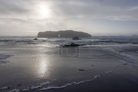 Photo for The ocean is calm and the sky is cloudy. The sun is shining through the clouds. The beach is rocky and the water is calm - Royalty Free Image