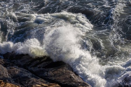 Téléchargez les photos : L'océan est rude et les vagues s'écrasent contre les rochers. L'eau est d'un bleu profond et le ciel est d'un bleu clair - en image libre de droit