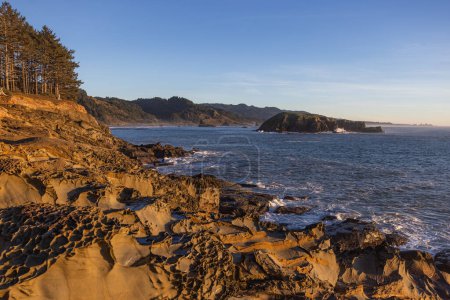 Téléchargez les photos : Un rivage rocheux avec un bel océan bleu en arrière-plan. Le ciel est clair et le soleil brille - en image libre de droit