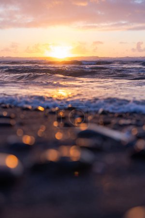 Téléchargez les photos : Le soleil se couche sur l'océan, projetant une lueur chaude sur l'eau. Les vagues sont douces, créant une atmosphère paisible - en image libre de droit