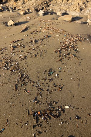 Téléchargez les photos : Une plage couverte de déchets et de débris. La plage est jonchée de bouteilles en plastique, de pailles et d'autres déchets. Concept de tristesse et de déception face à l'état de notre environnement - en image libre de droit