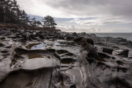 Téléchargez les photos : Un rivage rocheux avec un plan d'eau en arrière-plan. Les rochers sont recouverts d'eau, créant un paysage unique et intéressant. La scène est calme et sereine, l'eau reflétant le ciel - en image libre de droit