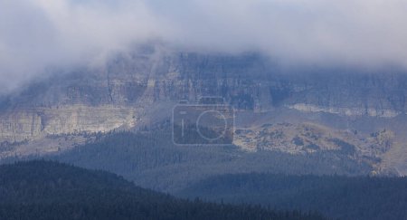 Photo for The mountain is covered in trees and has a cloudy sky. The clouds are low and grey, giving the scene a moody and somber atmosphere - Royalty Free Image