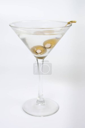 Téléchargez les photos : Un verre de martini rempli d'huile d'olive et d'olives. Le verre est à moitié plein et les olives flottent dans le liquide - en image libre de droit