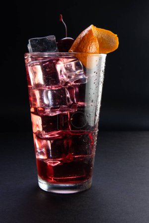 Téléchargez les photos : Un verre de boisson rouge avec des glaçons et une cerise sur le dessus - en image libre de droit