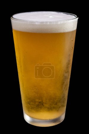 Téléchargez les photos : Un verre de bière est assis sur une table. Le verre est à moitié plein et a une tête mousseuse sur le dessus. Concept de détente et de plaisir, car la bière est une boisson populaire pour se détendre et socialiser - en image libre de droit