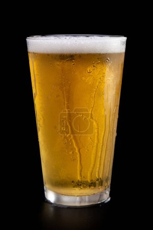 Photo for A glass of beer is sitting on a table. The glass is full and has a few droplets of water on the side. Concept of relaxation and enjoyment, as the beer is a popular beverage for unwinding - Royalty Free Image