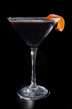 Photo for A martini glass with a slice of orange peel on top. The glass is filled with a dark liquid - Royalty Free Image