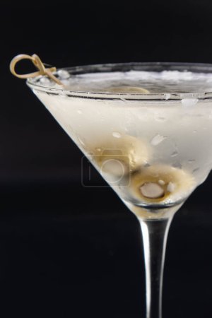 Téléchargez les photos : Vodka martini glacée aux olives farcies au fromage bleu isolées sur un fond noir - en image libre de droit