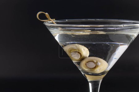 Téléchargez les photos : Vodka martini glacée aux olives farcies au fromage bleu isolées sur un fond noir - en image libre de droit