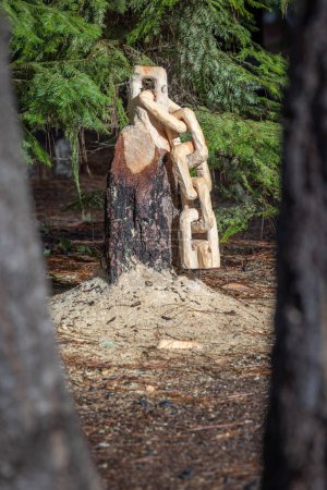 Foto de Una cadena está tallada de un tronco de árbol con polvo de sierra en el suelo. La escena es pacífica y serena. - Imagen libre de derechos