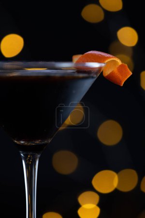 Photo for A martini glass with a slice of orange on top. The glass is filled with a dark liquid, and the orange slice adds a pop of color and a hint of sweetness to the drink - Royalty Free Image