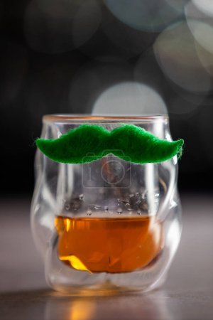 Photo for A glass with a mustache on it. The glass is filled with whiskey. The mustache adds a playful and whimsical touch to the glass for St Patrick's day. - Royalty Free Image