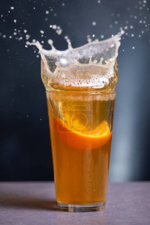 Téléchargez les photos : Un verre de bière avec une tranche d'orange dedans éclaboussant du verre - en image libre de droit
