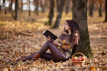 die schöne Frau liest im Herbst ein Buch mit einem Glas Wein in der Hand