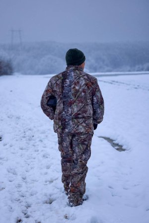 Téléchargez les photos : Un photographe masculin en tenue de camouflage dans un paysage hivernal - en image libre de droit