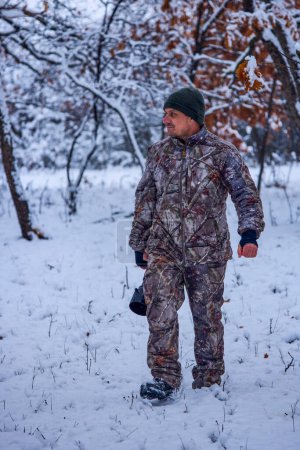 Téléchargez les photos : Un photographe masculin en tenue de camouflage dans un paysage hivernal - en image libre de droit