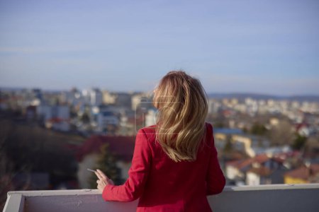 Foto de Una mujer en el balcón fumando en un día soleado. - Imagen libre de derechos