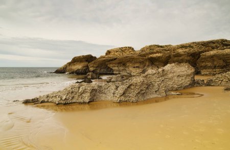 Photo for Cantabria, small wave-cut beach Playa del Bocal, light sand and eroded rock cliffs - Royalty Free Image