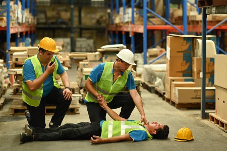 Photo for Shot of warehouse workers are helping and giving the injured first aid to colleague lying unconscious on concrete floor. - Royalty Free Image