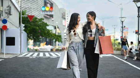 Téléchargez les photos : J'ai apprécié deux jeunes femmes avec des sacs à provisions marchant le long de la rue de la ville. Shopping, tourisme et mode de vie concept. - en image libre de droit