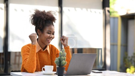 Excited African American woman reading email with good news on laptop, motivated by great offer or new opportunity.