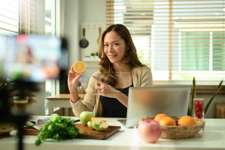 Foto de Blogger nutricionista femenina sosteniendo apio, proporcionando consultas en línea o grabando contenido de video en un teléfono inteligente. - Imagen libre de derechos