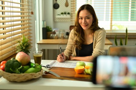Foto de Blogger nutricionista femenina sosteniendo apio, proporcionando consultas en línea o grabando contenido de video en un teléfono inteligente. - Imagen libre de derechos