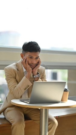 Téléchargez les photos : Tourné d'un jeune homme d'affaires regardant l'écran d'ordinateur portable, pensant à la solution de problème coincé avec la tâche. - en image libre de droit