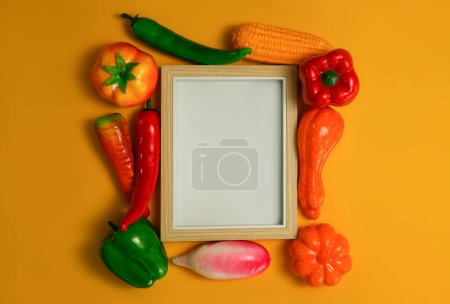 Foto de Marco de madera en blanco con verduras sobre fondo naranja, Fondo de comida saludable, concepto de comida vegetariana. - Imagen libre de derechos