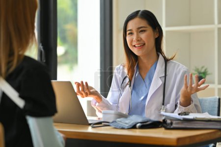 Foto de Hermosa doctora en uniforme médico blanco dando consulta, explicando el tratamiento a la paciente femenina. - Imagen libre de derechos