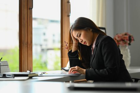 Téléchargez les photos : Femme entrepreneur frustrée tenant sa main se sentant fatiguée et stressée alors qu'elle était assise au bureau. - en image libre de droit