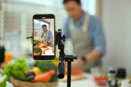Foto de Hombre de mediana edad grabando contenido de vídeo sobre alimentos saludables en el teléfono inteligente. - Imagen libre de derechos