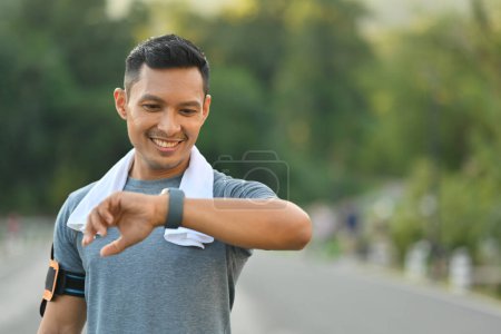 Photo for Young athlete checking fitness progress on his smart watch after training outdoors. - Royalty Free Image