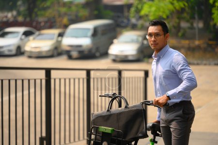 Businessman pushing bicycle while going to work on a sunny morning. Eco transportation.