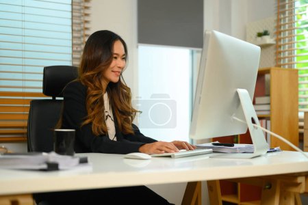 Foto de Tiro de millennial empresaria escribiendo en el teclado de la computadora respondiendo correo electrónico de negocios por la mañana. - Imagen libre de derechos