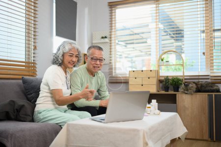 Foto de Anciano y mujer sentados frente a un portátil que tiene una videollamada en línea con el médico. Concepto de telesalud. - Imagen libre de derechos