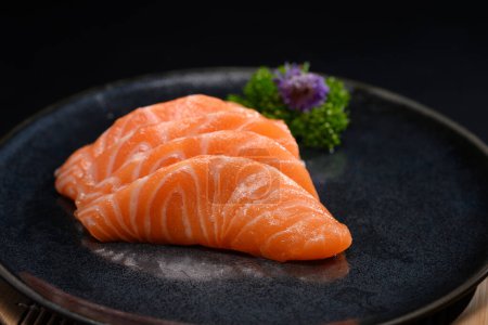 Foto de Sashimi de salmón en plato negro con hoja de perejil. Estilo de comida japonesa. - Imagen libre de derechos