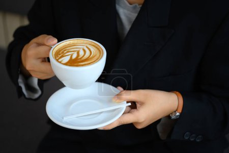 Gros plan de la jeune femme tenant une tasse de café avec latte art.