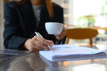 Foto de Empresaria haciendo papeleo y tomando café en el escritorio de la oficina. - Imagen libre de derechos