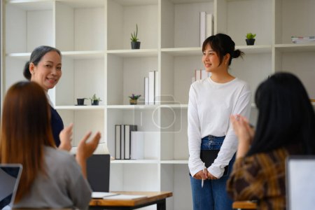 Foto de Sonriente asiática estudiante mujer teniendo presentación mientras su compañeros de clase dando aplausos. - Imagen libre de derechos