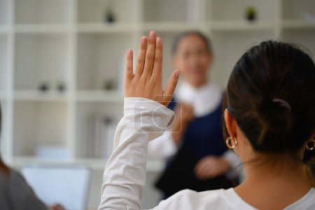Foto de Vista posterior de la estudiante universitaria levantando la mano para responder a una pregunta durante la conferencia. - Imagen libre de derechos