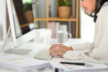 Foto de Joven empresaria escribiendo en el teclado de la computadora respondiendo correo electrónico de negocios por la mañana. - Imagen libre de derechos