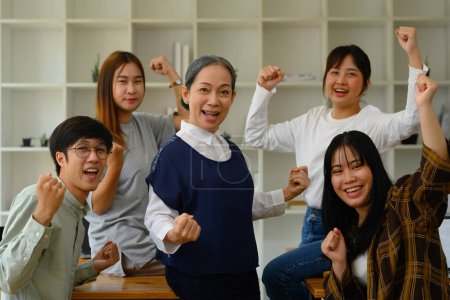 Foto de Grupo de estudiantes universitarios felices y profesor maduro celebrando el éxito en el aula. - Imagen libre de derechos